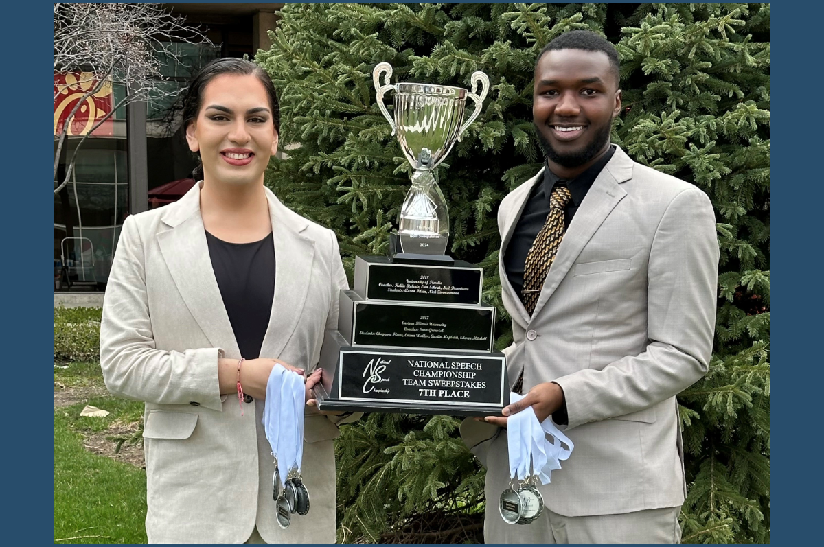 Two people in light suits holding trophy and medals